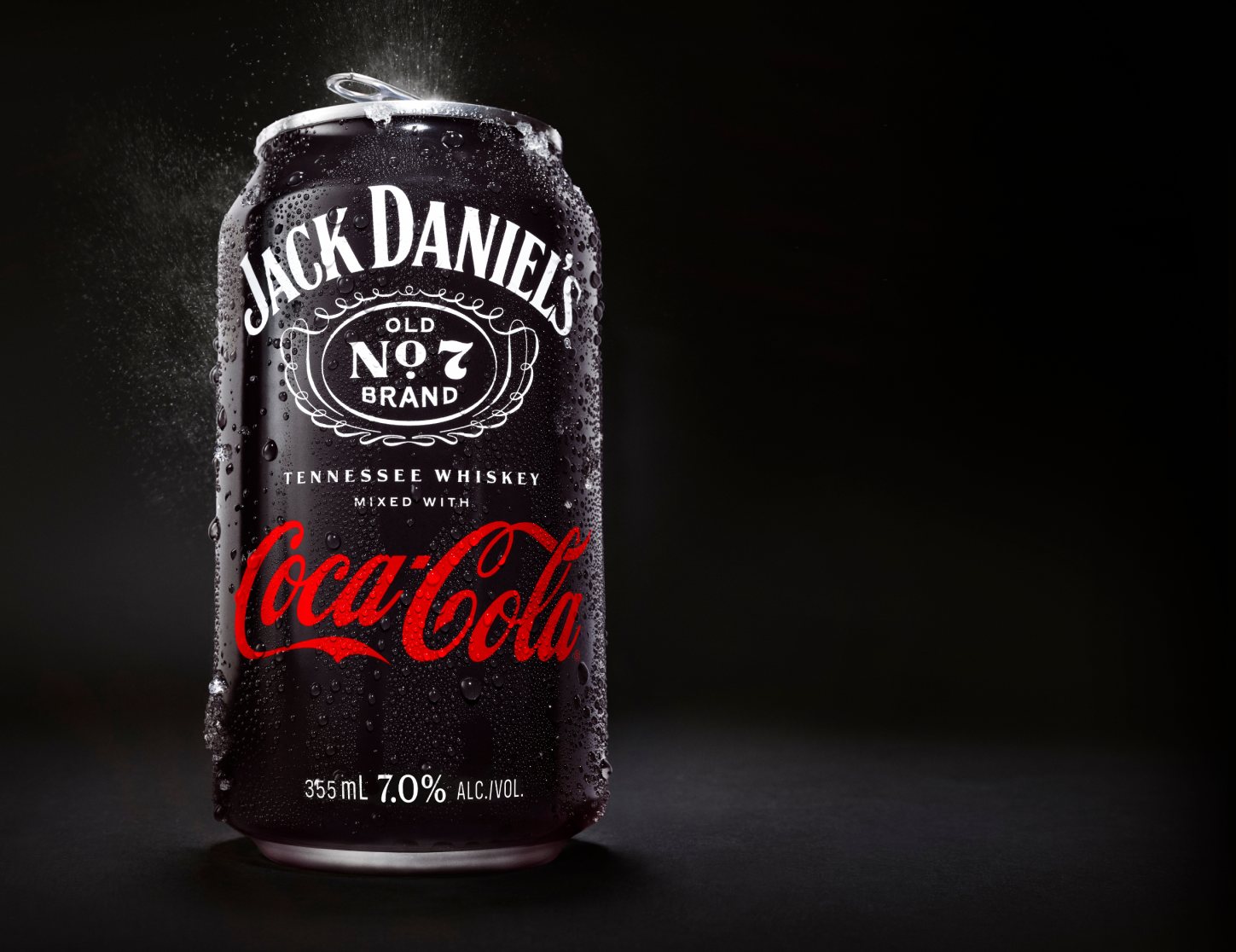 Image of the Jack Daniel's and Coca-Cola can with water sweat on the can and tab popping open with an explosion of water and carbonation on a black background.